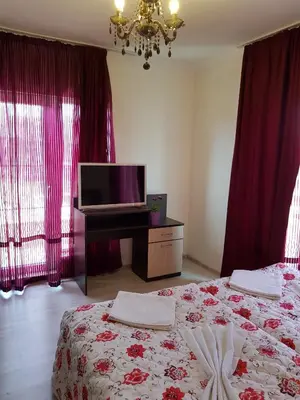 a bedroom with two beds and a television and red curtains at Family Aparthotel Vintegra in Burgas City