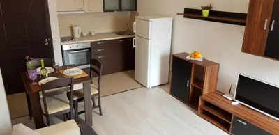 a small kitchen with a table and a white refrigerator at Family Aparthotel Vintegra in Burgas City