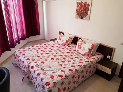 a bedroom with a bed with a red and white blanket at Family Aparthotel Vintegra in Burgas City