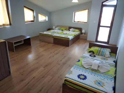 two beds in a room with wooden floors and windows at Guest House Niya Chernomorets in Chernomorets