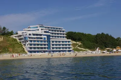 a large building on a beach next to the water at Aurora apartments on the beach in Obzor