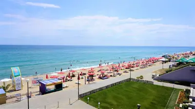 a beach with umbrellas and people on the beach at Aurora apartments on the beach in Obzor