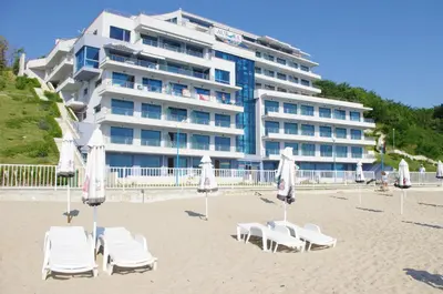 a hotel with chairs and umbrellas on a beach at Aurora apartments on the beach in Obzor
