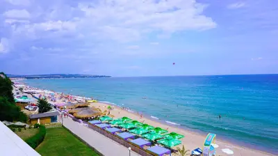 a beach with green umbrellas and crowds of people at Aurora apartments on the beach in Obzor