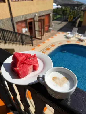 a plate of watermelon and a cup of coffee next to a pool at Complex Terazini in Byala