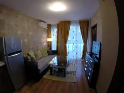a living room with a couch and a table and a television at VIP Apartments Dobrevi in Primorsko
