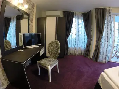 a hotel room with a desk with a television and a chair at VIP Apartments Dobrevi in Primorsko