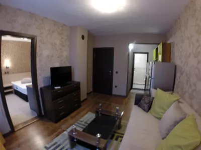 a living room with a couch and a television at VIP Apartments Dobrevi in Primorsko