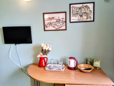 a table with a television and a table with flowers on it at Guest House Maria in Nesebar