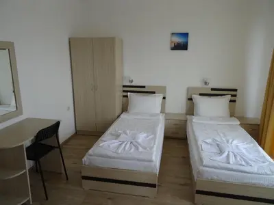two beds in a room with a table and a desk at The Sea Lions Guest House in Tsarevo