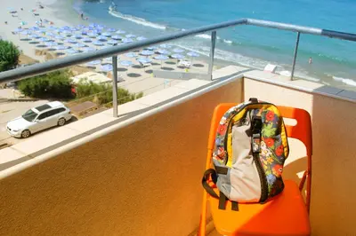 a backpack sitting on a chair on a balcony overlooking the beach at Beach Apartment MELINA in Pomorie