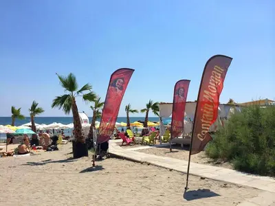 a row of flags on a beach with people on the beach at Beach Apartment MELINA in Pomorie