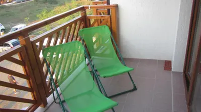 two green chairs sitting on top of a balcony at Apartments Resort BG in Primorsko