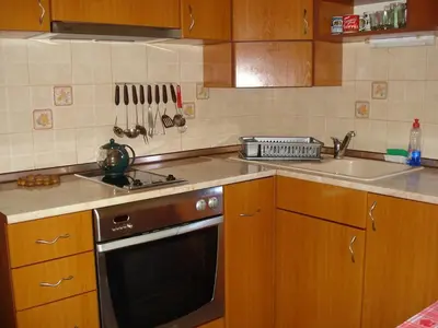 a kitchen with wooden cabinets and a black dishwasher at Dom Eli in Pomorie