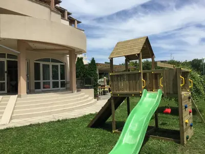 a playground with a green slide in a yard at Aparthotel Lucky Family in Ravda