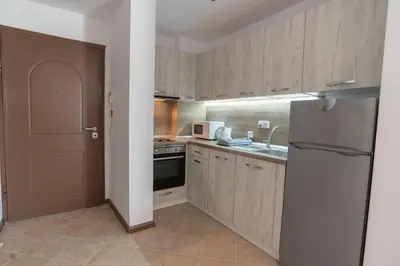 a kitchen with wooden cabinets and a refrigerator at Oasis Resort & Spa Cozy Apartments in Lozenets