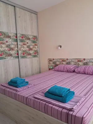 a bed with two blue towels on top of it at Apart Hotel Iglika in Pomorie