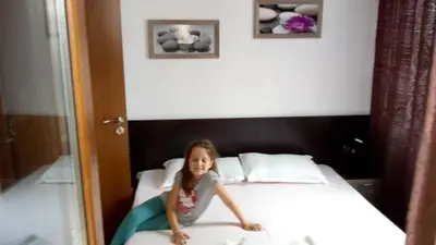 a young girl is sitting on a bed at Villa Maria in Tsarevo