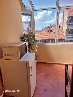 a microwave sitting on top of a refrigerator in front of a window at Homestay Kostadinov in Pomorie