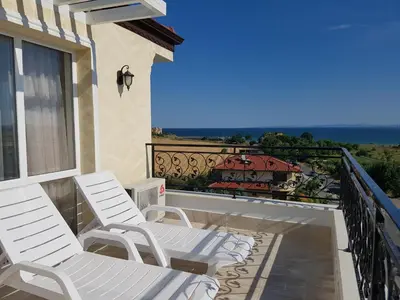 a balcony with white chairs and a view of the ocean at семеен хотел Прованс Ахелой in Aheloy
