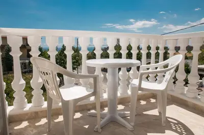a white fence with two chairs and a table on a balcony at семеен хотел Прованс Ахелой in Aheloy