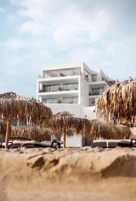 a beach with some straw umbrellas and a building at Sea Sense Boutique Villa & Relax Zone in Sozopol