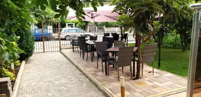 a patio with tables and chairs in a garden at Guest house Sineva in Primorsko