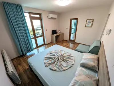 a room with a bed and a couch and a window at Guest house Sineva in Primorsko