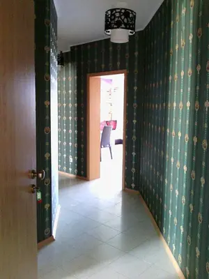 a hallway with green wallpaper and a chair in a room at Complex Oazis in Ravda