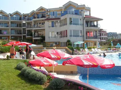 a pool with red umbrellas and a hotel at Apartments in Complex Panorama in Sozopol