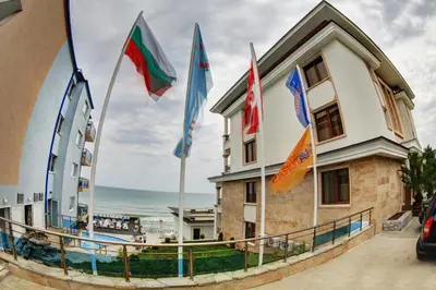 a building with flags in front of the ocean at Paraiso Theopolis - All Inclusive in Obzor
