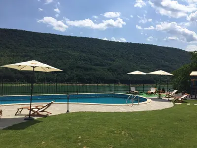 a swimming pool with two chairs and an umbrella at Eco House Kitana in Tschenge