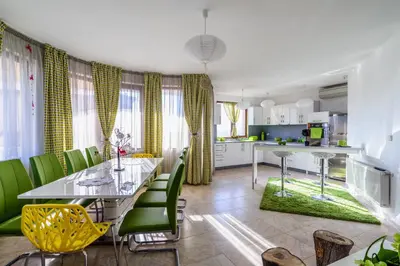 a kitchen and dining room with a table and green chairs at Villa Maja in Varna City