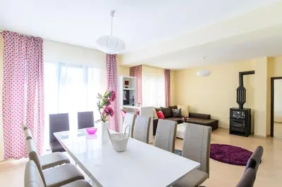 a dining room and living room with a white table and chairs at Galata Residence in Varna City