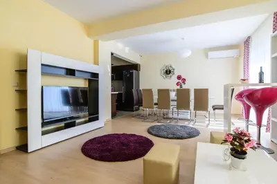 a living room with a large television and a dining room at Galata Residence in Varna City