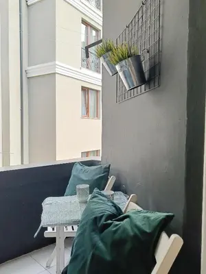 a balcony with green pillows and a table and a window at Apartment Balabanov in Varna City