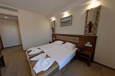 a bedroom with a bed with white sheets and a mirror at Hotel Aristokrat in Obzor
