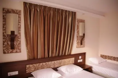 a bedroom with two beds and a window with two mirrors at Hotel Aristokrat in Obzor