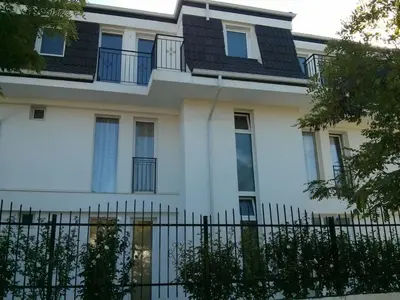 a white building with windows and a fence at Belvedere Apartments in Byala