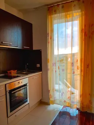 a kitchen with a stove and a window with curtains at Belvedere Apartments in Byala