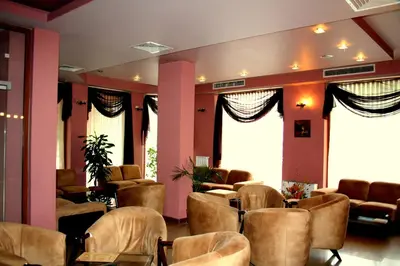 a waiting room with chairs and tables and windows at Hotel Elegant in Karnobat