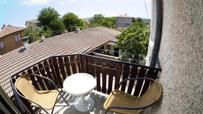 a balcony with two chairs and a table and a building at Atanasovi House in Shkorpilovtsi