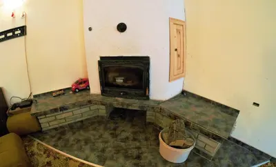 a living room with a fireplace in the corner at Atanasovi House in Shkorpilovtsi