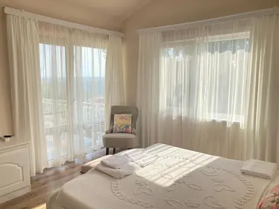 a bedroom with a bed and a chair and windows at Vila Sofia - Pool, Sauna & Nature Escape in Varna City
