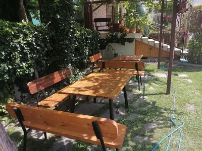 a group of wooden benches sitting in the grass at St. George Guest House in Sveti Vlas