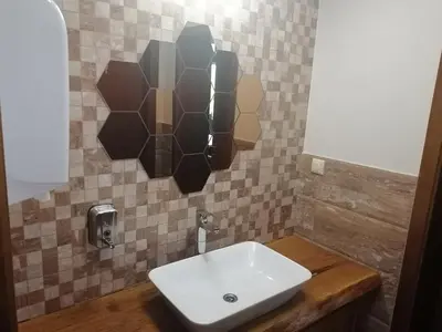a bathroom with a white sink and a tiled wall at St. George Guest House in Sveti Vlas