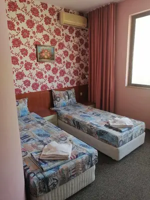 a hotel room with two beds and a window at St. George Guest House in Sveti Vlas