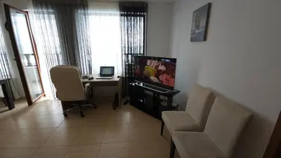a living room with a table and a desk with a laptop at Complex Top Apartment in Sveti Vlas