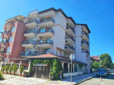 a tall white building with balconies on a street at Kovachevi House in Primorsko