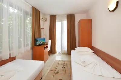 a hotel room with two beds and a television at Nirvana Guest House in Nesebar